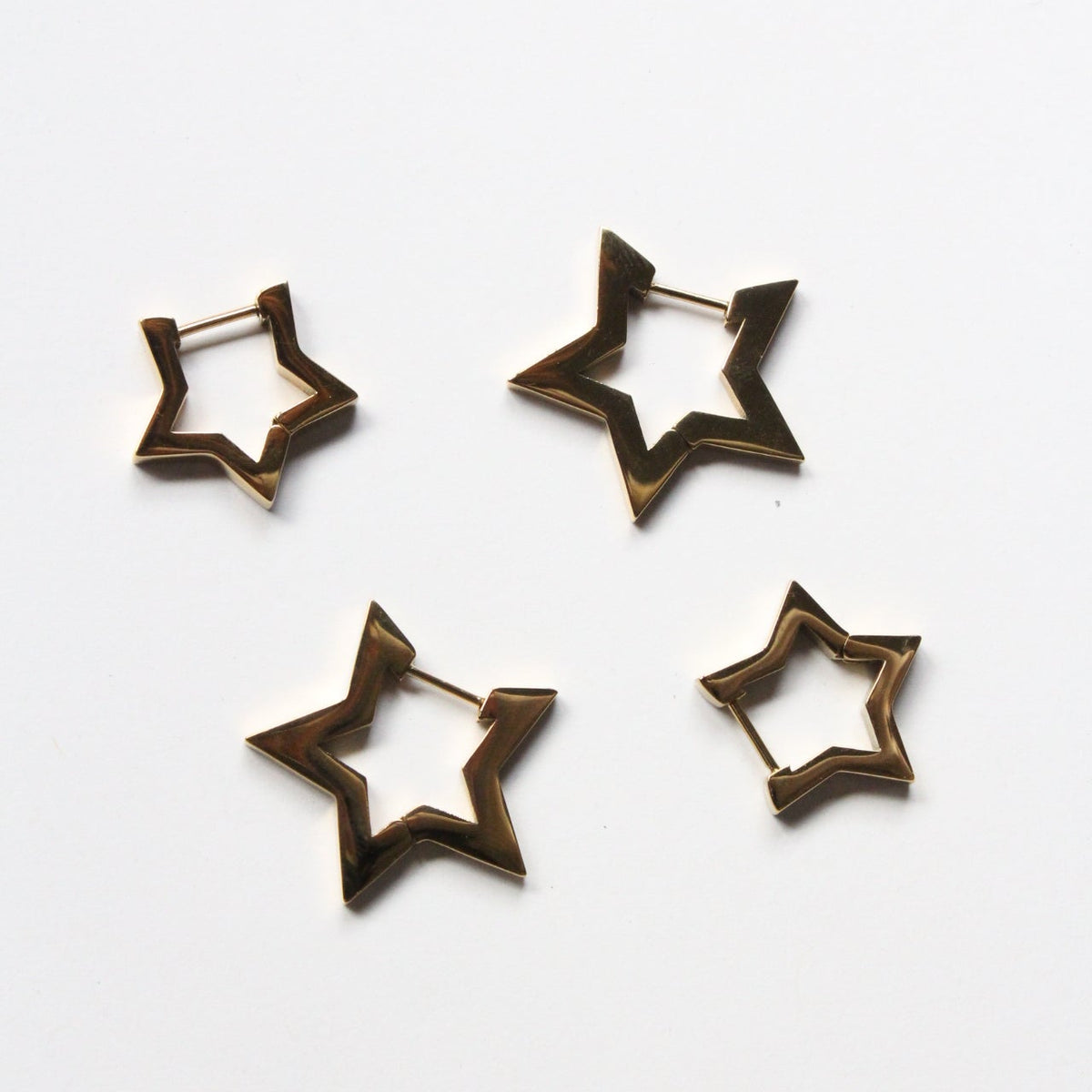 Four open star-shaped hoop earrings in a dark bronze metal finish, arranged on a plain white background.