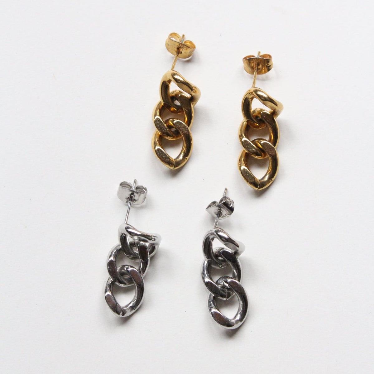 Two pairs of dangling chain-link earrings on a plain white background, one in polished gold and one in polished silver.