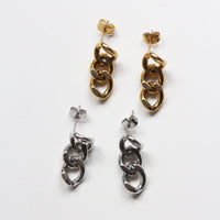 Two pairs of dangling chain-link earrings on a plain white background, one in polished gold and one in polished silver.
