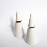 White earbuds with gold accents on a light grey  background, waterproof and hypoallergenic ring flat signet design
