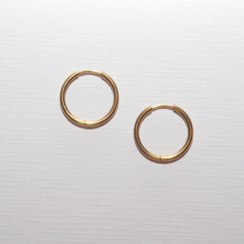 A pair of thin gold hoop earrings on a light gray textured background.