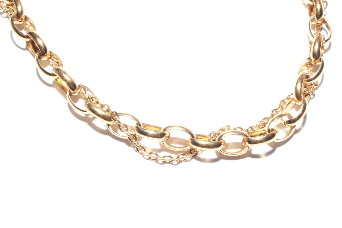 A close-up of a gold-toned chain necklace featuring alternating thick oval links and delicate fine chain sections, set against a plain white background.