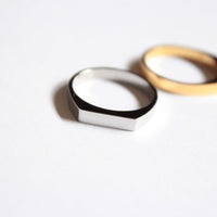 Two rings, one white and one gold, on a light gray background