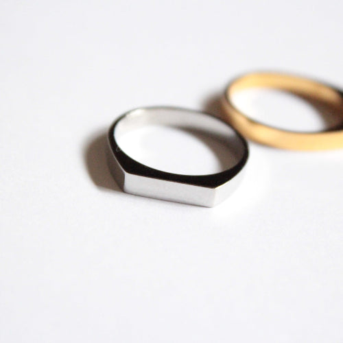 Two rings, one white and one gold, on a light gray background