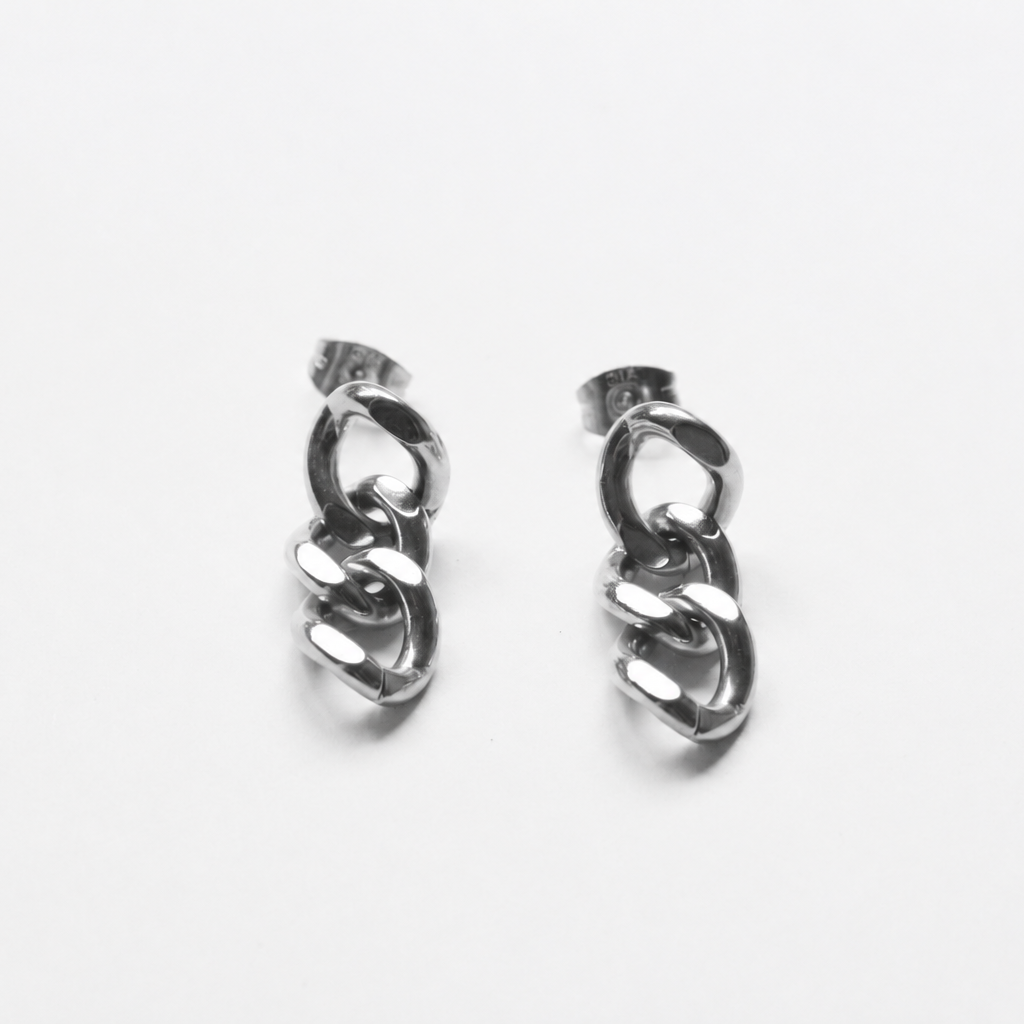 A pair of silver-toned huggie hoop earrings with a twisted chain link design, displayed on a clean white background.