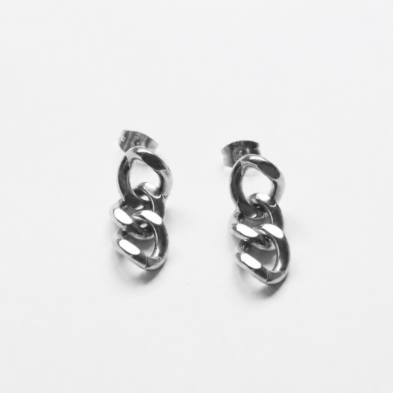 A pair of silver-toned huggie hoop earrings with a twisted chain link design, displayed on a clean white background.