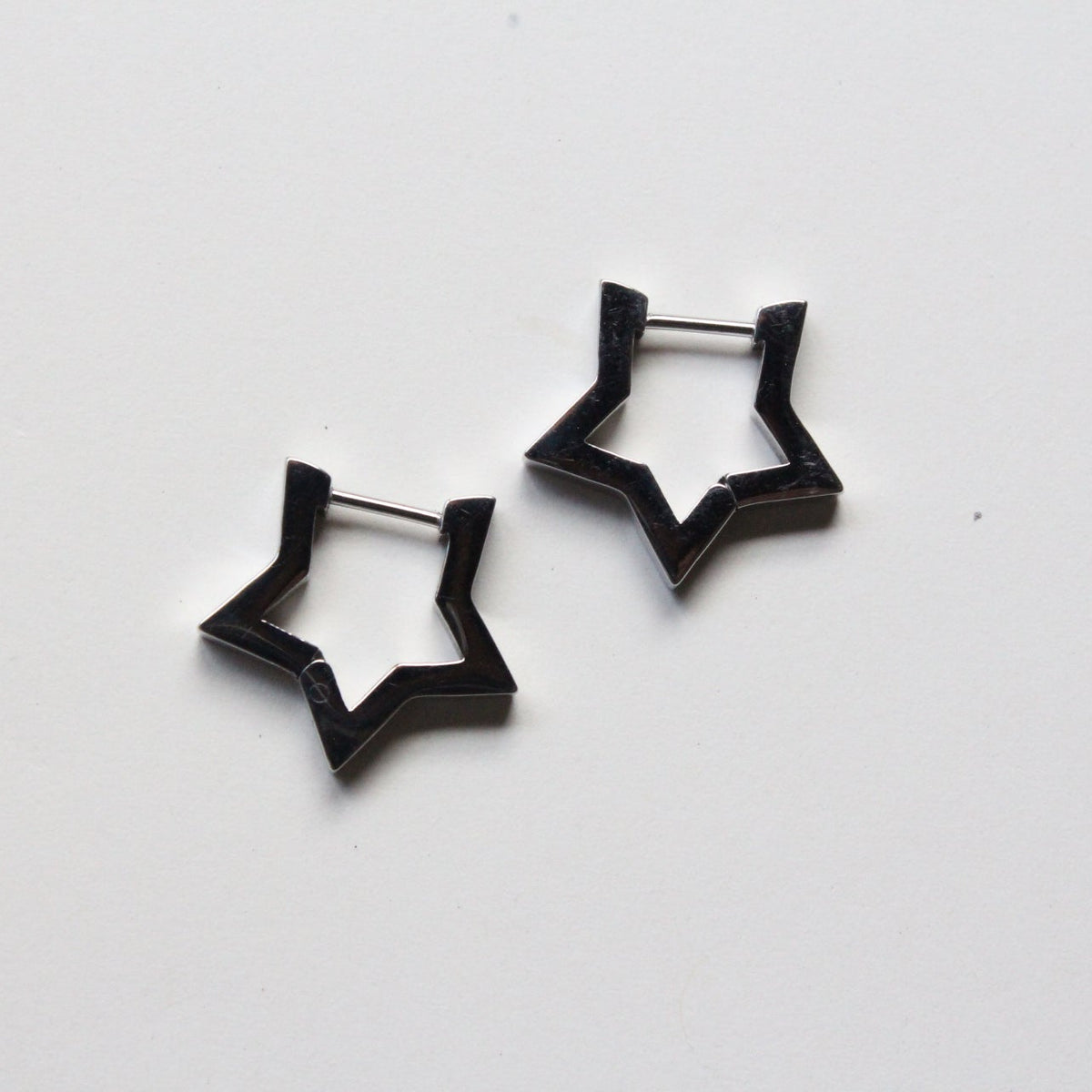 A pair of silver star-shaped hoop earrings on a plain white background.