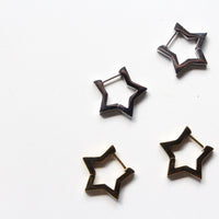 Four star-shaped hoop earrings with a dark metallic finish, arranged on a plain white background.