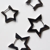 Four silver star-shaped hoop earrings with silver-toned posts, arranged on a plain white surface.