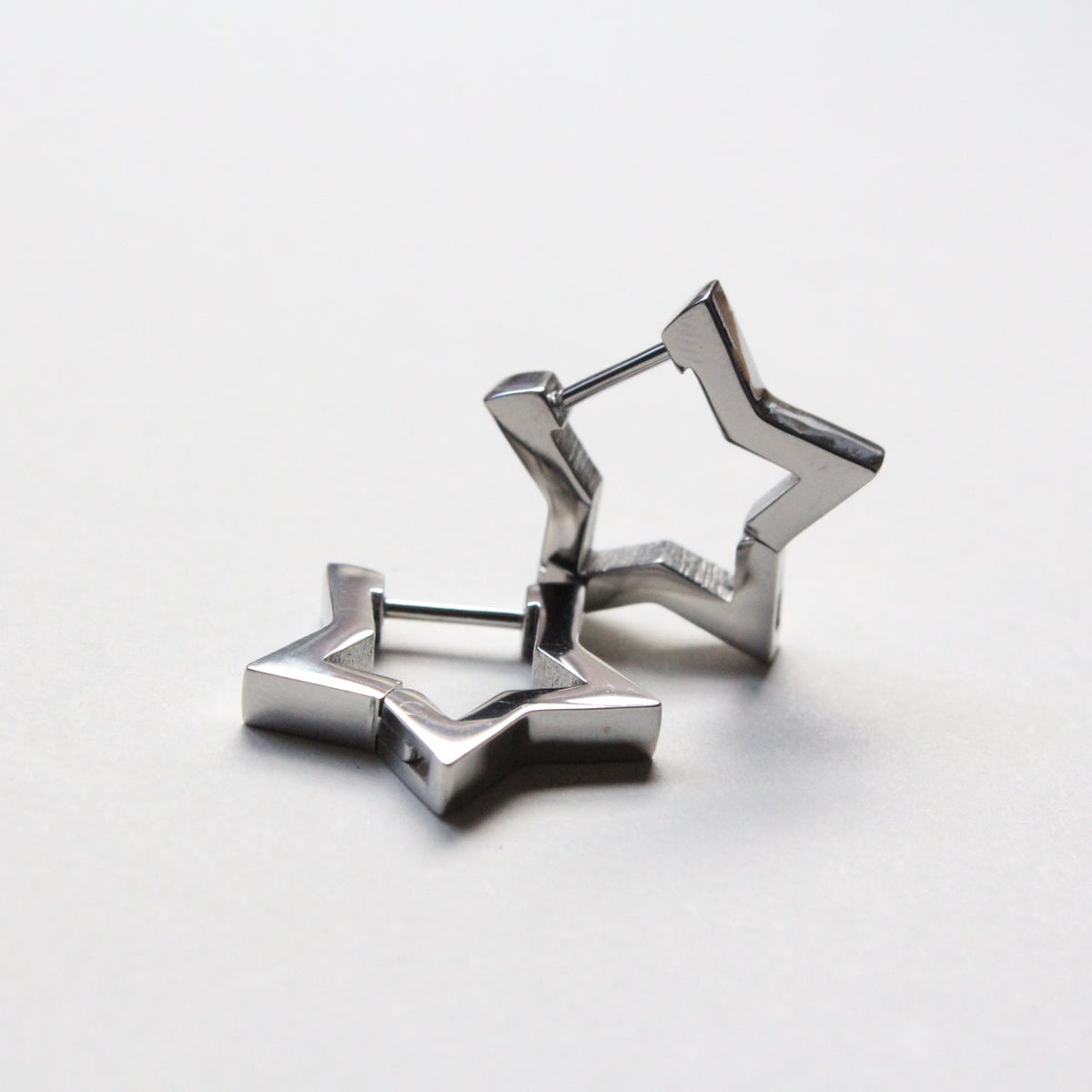 A pair of silver-toned geometric star-shaped earrings on a clean white background.